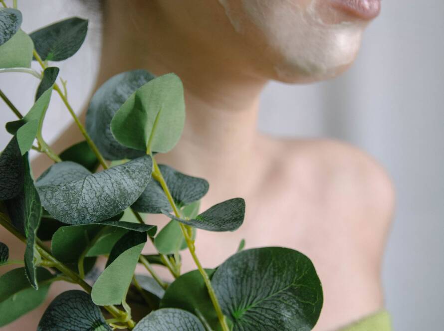 Mulher aplicando creme facial com folhas naturais, simbolizando a abordagem holística da dermatologia integrativa em BH