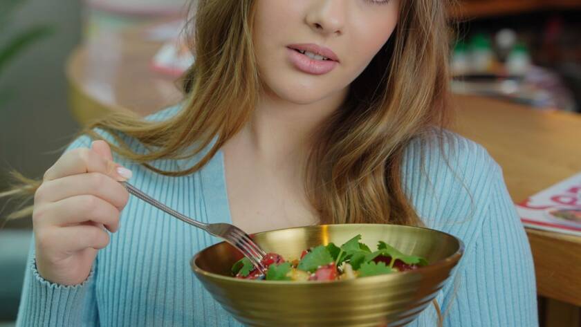 Mulher se alimentando com salada colorida, simbolizando nutrição para a saúde da pele na dermatologia integrativa em BH