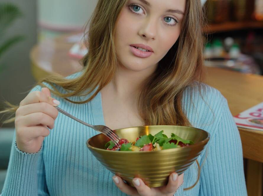 Mulher se alimentando com salada colorida, simbolizando nutrição para a saúde da pele na dermatologia integrativa em BH