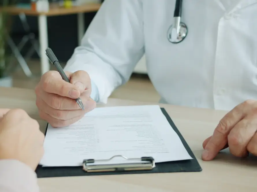 Médico dermatologista escrevendo no prontuário durante consulta em Belo Horizonte