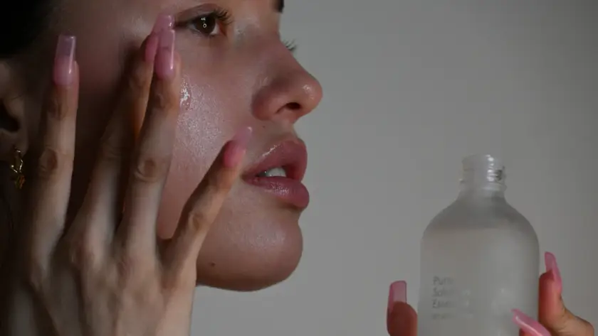 Mulher aplicando sérum no rosto, etapa da rotina de skincare recomendada por dermatologista