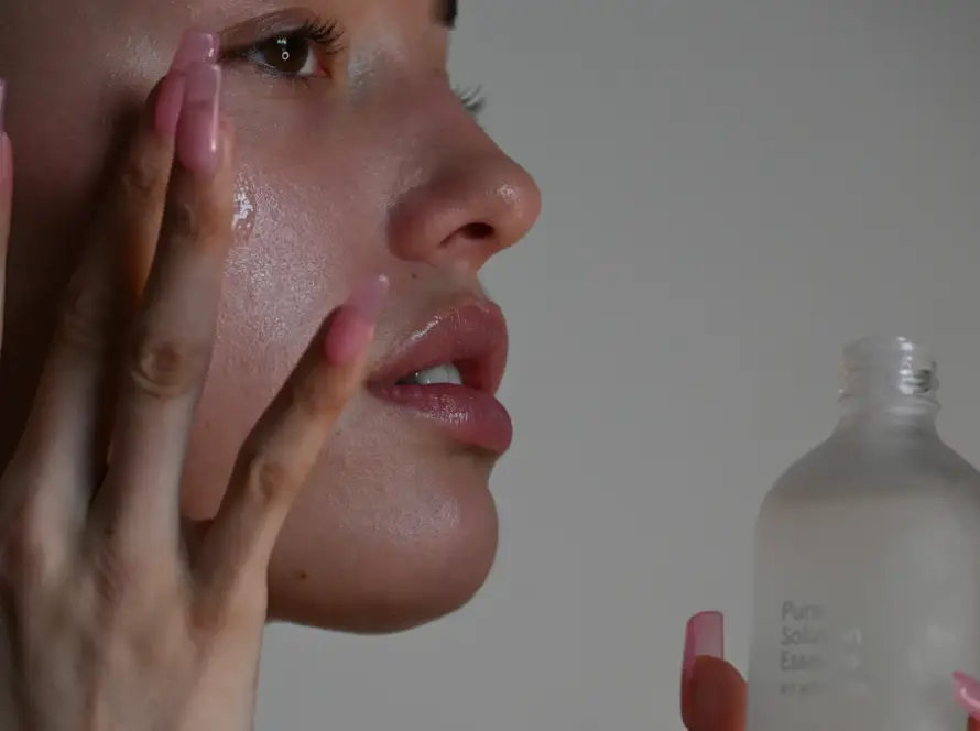 Mulher aplicando sérum no rosto, etapa da rotina de skincare recomendada por dermatologista